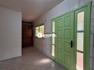 Hall de entrada com piso de cerâmica e portas verdes na residência.