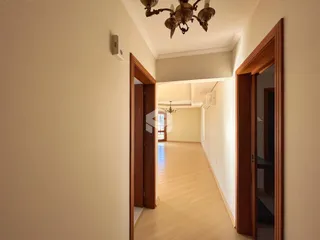 Corredor interno de uma residência com piso de madeira e portas de madeira.