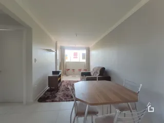 Interior de uma sala com sofá e piso de madeira.