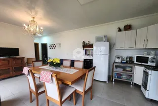 Sala de jantar com mesa de madeira e ambiente iluminado.