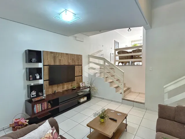 Sala de estar com parede de TV e escadaria visível.