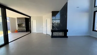 Sala de estar ampla com piso de porcelanato e lareira de mármore escura.