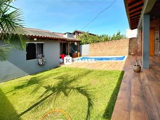 Foto da fachada de uma casa com piscina e gramado verde.