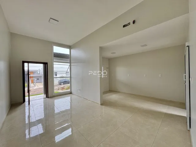 Sala de estar ampla com piso de cerâmica clara e paredes brancas.