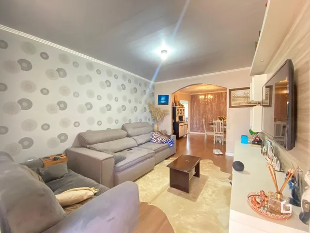 Sala de estar com sofá grande e decoração clara em um imóvel no Brasil.