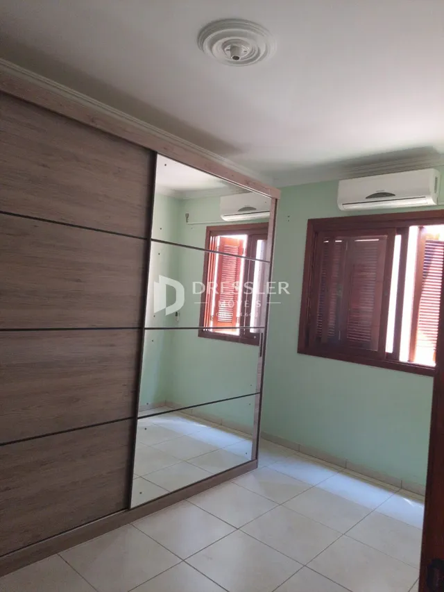 Parede interna de uma residência em Lajeado, Brasil, com painéis de madeira e um espelho refletindo o ambiente.
