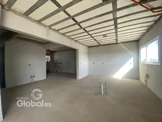 Espaço interno de uma construção em reforma com teto de vigas exposto.
