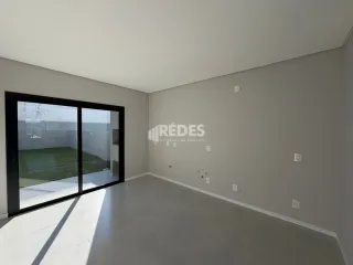 Vista interna de um cômodo com piso e paredes brancas em uma residência.