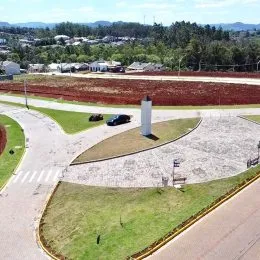 Vista de um terreno aberto com área gramada e estrada de acesso.
