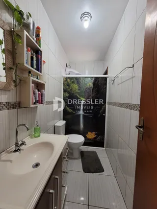 Banheiro com piso e paredes brancas no imóvel.