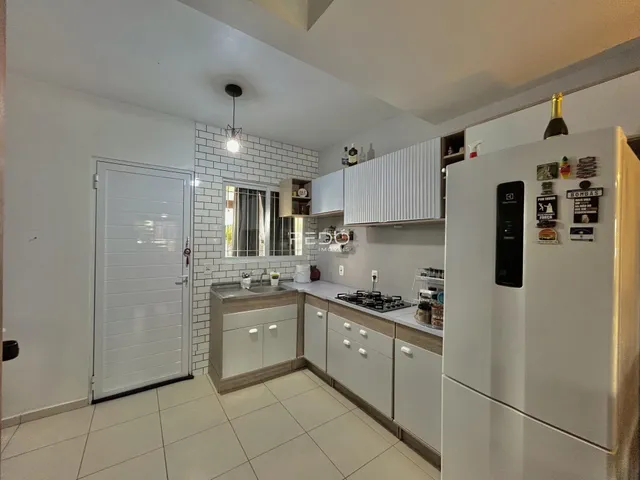 Cozinha moderna com armários brancos e piso claro.