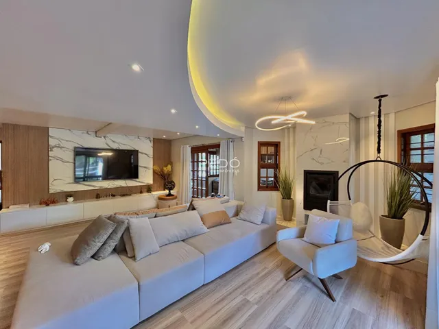 Sala de estar moderna com sofá claro e piso de madeira no imóvel.