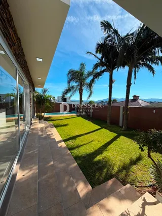 Vista externa de uma propriedade com jardim e palmeiras.