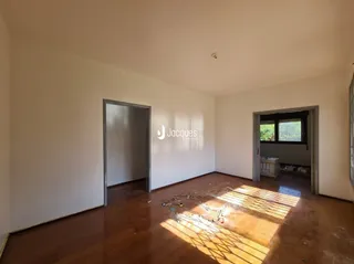 Interior de uma sala com piso de madeira e luz natural entrando pela porta.