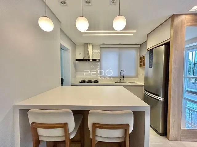 Vista de uma cozinha moderna com ilha e armários brancos.