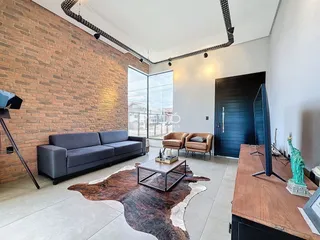 Sala de estar com parede de tijolos aparentes e sofá cinza.
