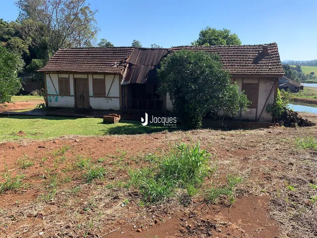 Fachada de uma casa rústica em Lajeado, Brasil, com terreno seco em primeiro plano.
