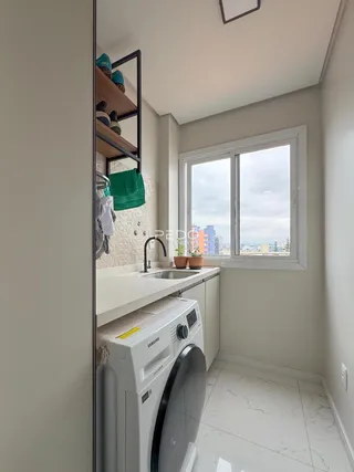 Foto de uma área de serviço com máquina de lavar e janela em um imóvel.
