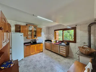Vista interna de uma cozinha com armários de madeira e piso cerâmico.