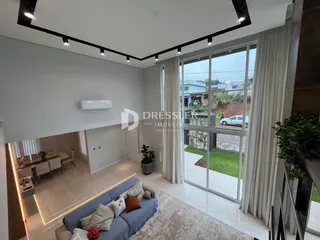 Sala de estar com grandes janelas que dão vista para o jardim externo.