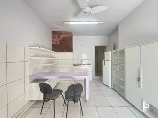 Interior de uma cozinha com piso de cerâmica e armários brancos.