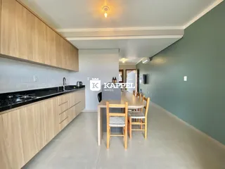 Foto de uma sala de jantar com mesa de madeira e cozinha moderna em um apartamento.