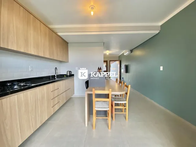 Foto de uma sala de jantar com mesa de madeira e cozinha moderna em um apartamento.