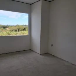Foto de um ambiente interno com paredes brancas e piso de concreto.