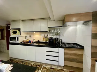 Cozinha moderna com armários brancos e bancadas escuras.