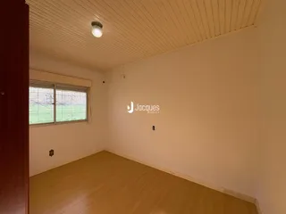 Interior de uma sala com piso de madeira clara e paredes brancas.