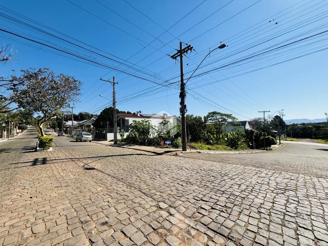 Vista da rua pavimentada em Lajeado, Brasil com casas residenciais ao fundo.