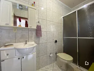 Foto interna de um banheiro com revestimento cerâmico claro.