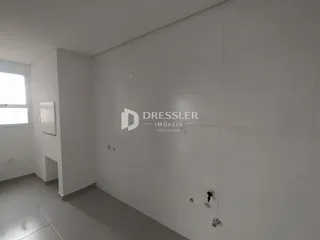 Vista interna de um corredor com paredes brancas e piso claro.