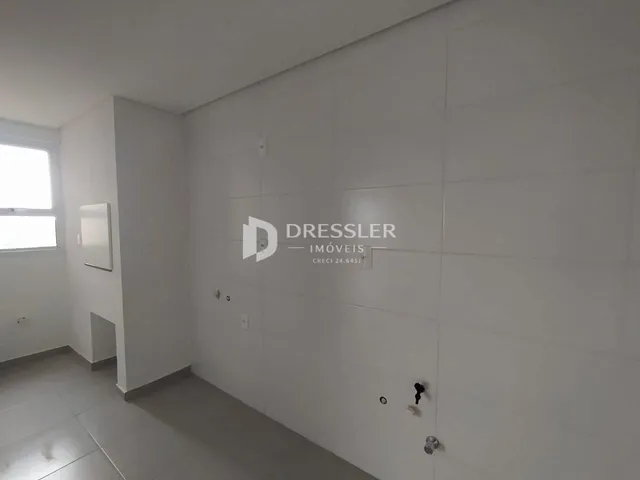 Vista interna de um corredor com paredes brancas e piso claro.