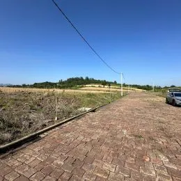 Paisagem aberta com um caminho de tijolos sob um céu azul claro.