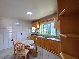 Foto de uma cozinha com armários de madeira e mesa de jantar em um imóvel.