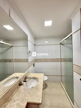 Banheiro com bancada de mármore e revestimento de azulejos brancos.