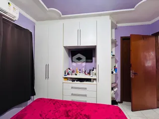 Quarto com armários brancos e parede roxa em um imóvel no Brasil.