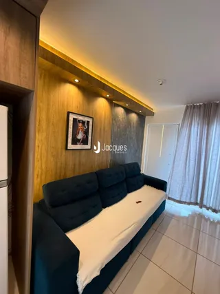 A sala apresenta um sofá azul e painéis de madeira na parede.