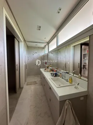 Vista de um banheiro com bancada e espelho em uma residência.