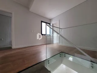 Vista interna de um ambiente com piso de madeira e divisória de vidro.