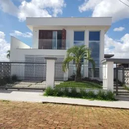Fachada branca de uma casa em Lajeado, Brasil, com cerca e paisagismo.