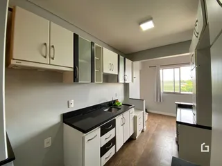 Uma cozinha moderna com armários brancos e bancadas escuras.