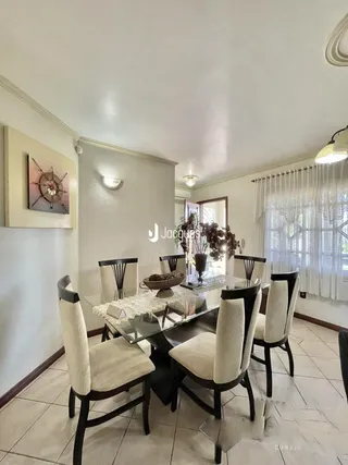 Uma sala de jantar com mesa e cadeiras em um imóvel no Brasil.