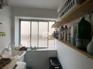 Vista interna de uma área com janela e prateleira em uma residência.