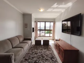 Sala de estar com sofá e televisão em um apartamento.