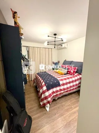 Foto de um quarto interno com cama e piso de madeira.