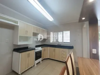 Cozinha com armários de madeira clara e bancadas escuras.