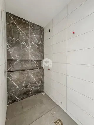 Parede com revestimento de mármore cinza e azulejos brancos em um ambiente interno.