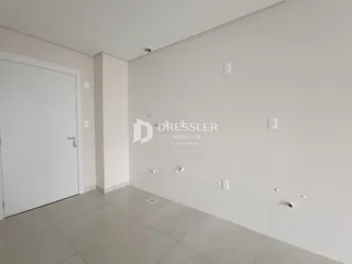 Vista interna de um corredor com paredes brancas e piso cinza claro.